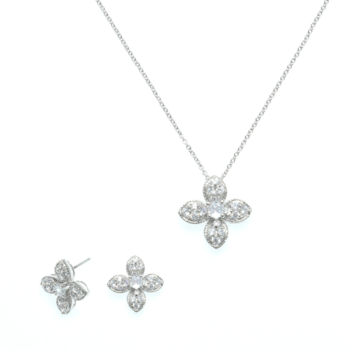 طقم مجوهرات الزهر الرباعي الناعم مع ترصيع مكثف بأحجار الزركون البيضاء الشفافة Delicate four-petal floral jewelry set, richly studded with clear white zircon stones.